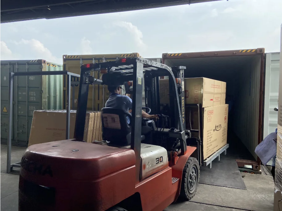 A forklift loading packed furniture into a shipping container